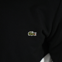 Détail du logo crocodile sur un sweatshirt LACOSTE noir, symbole de style et confort.